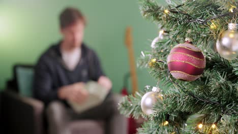 Der-Mann-Ist-Aufgeregt,-Ein-Geschenk-Am-Weihnachtsmorgen-Mit-Einem-Weihnachtsbaum-Im-Vordergrund-Auszupacken