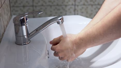 Mann,-Der-Seine-Hände-Mit-Kaltem-Wasser-Im-Badezimmer-Spült