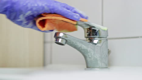 Caucasian-hand-with-purple-glove-washes-faucet-to-prevent-coronavirus