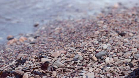 Close-up-still-shot-of-clear-gentle-water-waves-breaking-on-rocky-shore