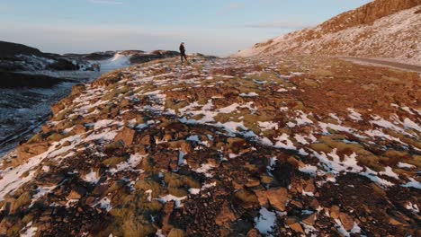 Ein-Mann,-Der-Am-Rand-Eines-Erodierten-Berges-Steht-Und-Die-Drohne-Bedient,-Um-Den-Wunderschönen-Sonnenuntergang-über-Dem-Vulkanischen-Land-In-Island-Einzufangen