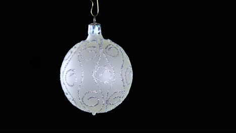 single-white-Christmas-ball-ornament-with-silver-glitter-stripes-and-black-background,-close-up