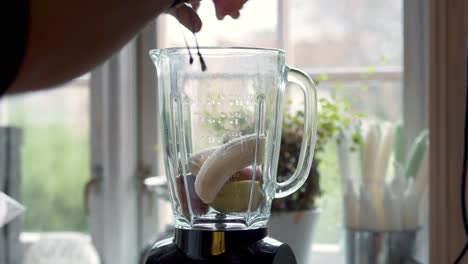 Person-putting-healthy-ingredients-into-a-blender-to-mix-a-healthy-smoothie