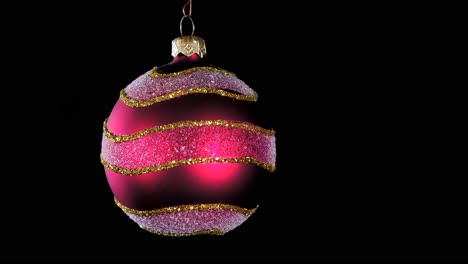 Single-Red-Christmas-Ball-Ornament-Mit-Goldenen-Silbernen-Glitzerstreifen-Und-Schwarzem-Hintergrund,-Nahaufnahme