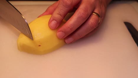 Woman-cutting-the-potatoes-on-the-board-in-the-kitchen