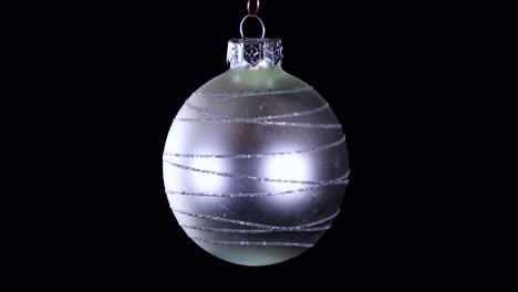 single-silver-Christmas-ball-ornament-with-glitter-stripes-and-black-background,-close-up
