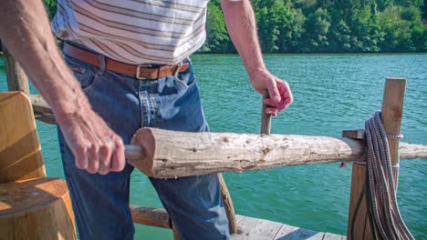Close-up-of-strong-raftsman-on-the-Drava-river-using-an-oar-to-steer-a-log-raft