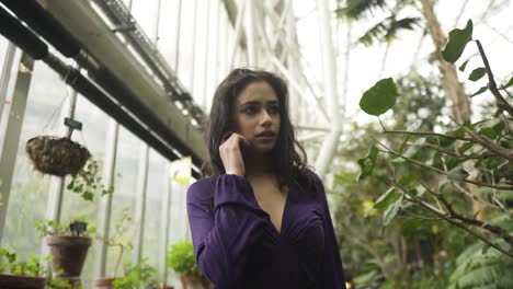 Young-indian-woman-in-gothic-outfit-walking-around-botanical-garden-in-greenhouse-looking-at-flowers-and-wondering-in-slowmotion