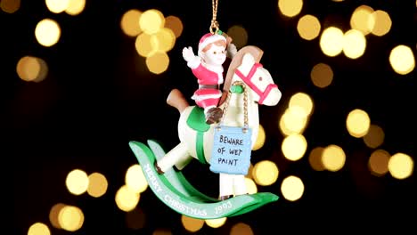 single-wooden-Christmas-ornament-of-a-boy-on-a-rocking-horse-with-out-of-focus-lights-flickering-in-the-background,-close-up