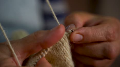 Hands-of-old-woman-knitting-handmade-wool-socks-with-needles-at-home,-slow-motion,-close-up-grandma