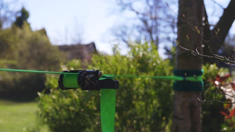 Closeup-of-bright-green-slack-line-and-ratchet-on-slightly-windy-but-very-sunny-day