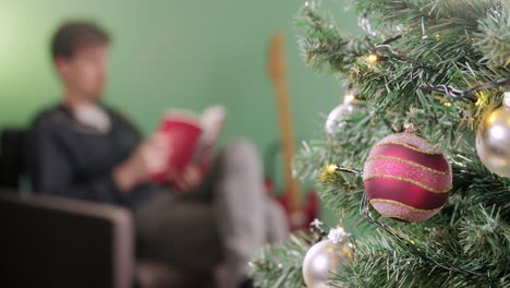 Mann-Entspannt-Sich-Mit-Einem-Buch-Am-Weihnachtsmorgen-Mit-Einem-Weihnachtsbaum-Im-Vordergrund