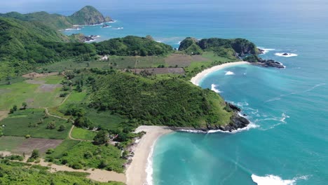Pull-back-aerial-shot-of-a-tropical-island,-with-agricultural-land-and-blue-ocean-hitting-the-coastline
