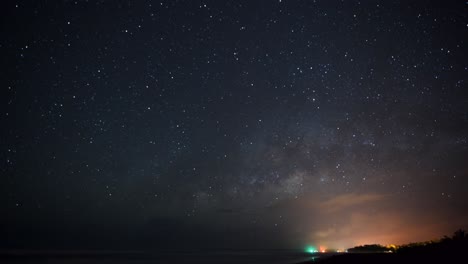 A-beautiful-Timelapse-of-the-night-sky-with-the-milky-way-getting-up-on-the-pacific-shore-of-Costa-Rica-in-march,-with-the-city-of-Cahuita-on-the-bottom