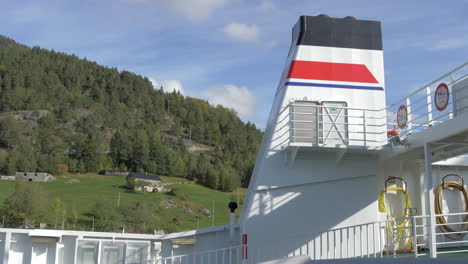 View-from-a-Norwegian-Ferry-Passing-by-a-Lush-Green-Mountainside-on-a-Sunny-Day,-Static