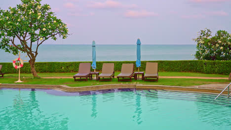 chair-pool-or-bed-pool-and-umbrella-around-swimming-pool-with-sea-background---Holidays-and-vacation-concept