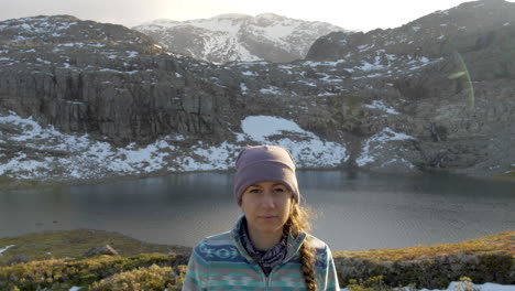 A-Woman-Looks-Towards-the-Camera-with-a-Calm-Expression-While-on-a-Sunset-Hike-on-a-Mountain-in-Norway,-Static-Slow-Motion