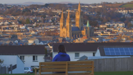 Person-sits-on-Bench-overlooking-Truro,-UK-Cathedral-at-Sunset-During-Lockdown,-zoom-in