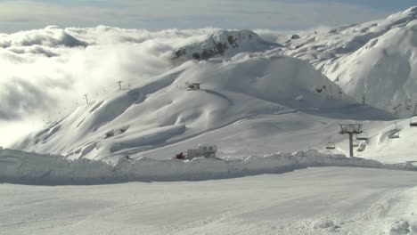 Wide-panning-shot-of-empty-ski-slope-above-clouds,-lots-of-snow,-Kanin-Slovenia