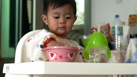 Lindo-Bebé-Asiático-Lamiendo-El-Dedo-Después-De-Comer-Fideos-De-Arroz-En-Casa