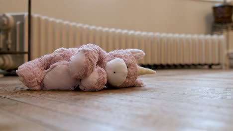 Still-shot-of-a-baby-toy-unicorn-sitting-on-the-floor-in-front-of-a-radiator-in-an-old-house