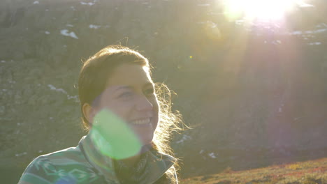 Close-Up-of-a-Woman-Smiling-and-Lauging-while-on-a-Sunset-Hike-on-a-Mountain-in-Norway,-Slow-Motion-with-Lens-Flares
