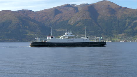 Un-Ferry-Noruego-Pasa-Por-Un-Fiordo-Con-Hermosas-Montañas-Al-Fondo-En-Un-Día-Soleado,-A-Cámara-Lenta