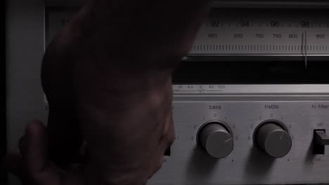 Slow-motion-hand-reaching-in-to-turn-on-power-switch-for-old-school-AM-FM-wireless-radio-player