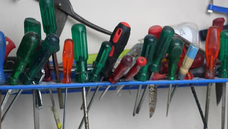 Slow-panning-clip-of-messy-work-space-shelf-with-screwdrivers-hanging-in-a-workshop