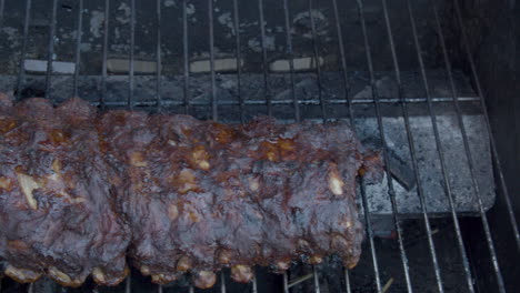 High-angle-pan-of-delicious-spareribs-being-grilled-on-barbecue---close