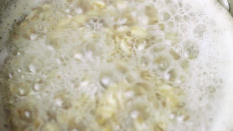 Close-up-of-oat-meal-boiling-and-bubbling-in-spirals-in-a-metal-sauce-pan-on-the-hob