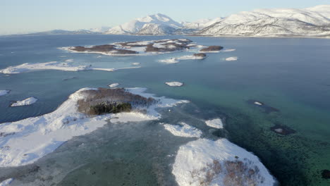 Vista-Aérea-De-Un-Archipiélago-Cubierto-De-Nieve-En-Las-Aguas-árticas-Azules-Brillantes-De-Noruega