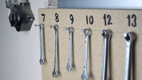 Slow-panning-clip-of-organized-wrenches-hanging-on-a-board-in-a-workshop