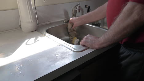Man-Cleaning-And-Wiping-A-Sink-in-The-Kitchen---Closeup-Shot