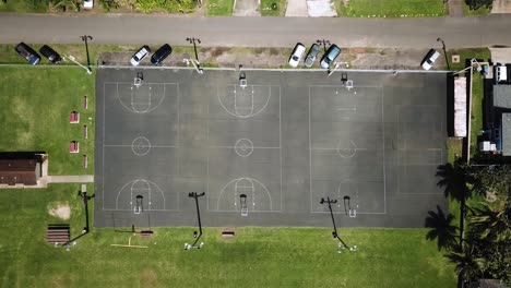 Closed-Basketball-courts-at-Laie-Park,-Hawaii,-lowering-aerial-birds-eye-view