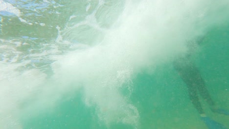 A-slow-motion-shot-from-under-the-water-of-a-wave-breaking-to-a-bodyboarder-sitting-out-in-the-surf