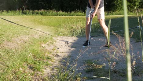 Ein-Golfspieler-Versucht,-Einen-Schuss-Aus-Einem-Sandbunker-Zu-Schlagen,-Während-Der-Golfball-An-Einem-Sonnigen-Tag-Aus-Dem-Sandbunker-Fliegt
