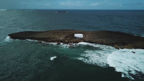 Waves-crashing-against-natural-sea-arch-at-Laie-Point,-O'ahu-Hawaii,-aerial-view