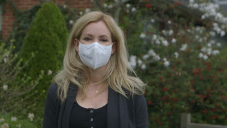 Attractive-woman-outside-puts-on-a-medical-mask-and-looks-into-camera