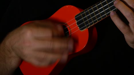 Musiker-Spielt-Einige-Akkorde-Auf-Einer-Orangefarbenen-Ukulele