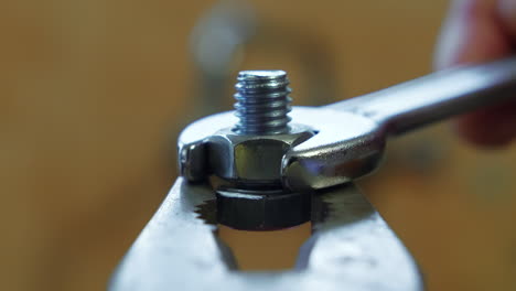 Clockwise-of-a-wrench-turning-a-bolt-on-a-screw-held-by-pliers,-close-up
