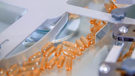Slow-motion-of-orange-gel-capsules-moving-inside-a-packaging-machine