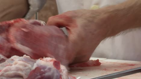 Butcher-cuts-big-piece-of-raw-meat-with-sharp-knife,-closeup