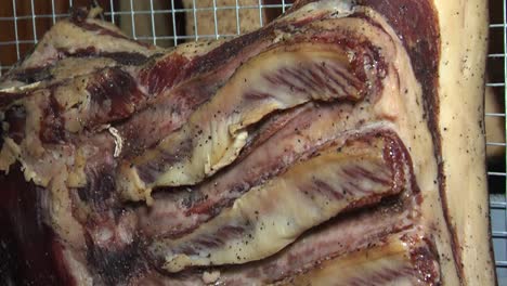 Dry-ageing-marinated-pork-ribs-hanging-in-cellar,-closeup-tilt-shot