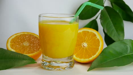 Studio-shot-of-full-glass-of-orange-juice-and-orange-halves,-closeup,-slow-pan