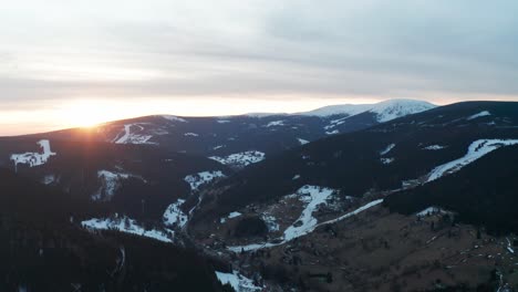 Aerial-view-of-the-sun-rising-over-snow-capped-mountains