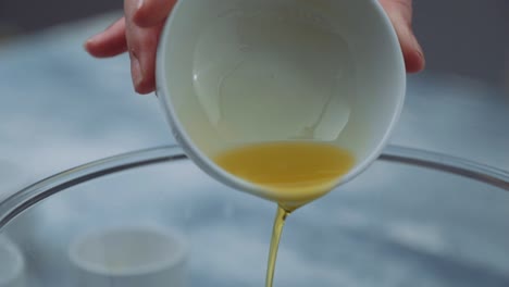 Pouring-olive-oil-from-a-small-white-ceramic-bowl-ramekin