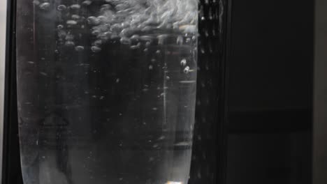 Slow-motion-carbonated-air-and-bubbles-being-pumped-into-canister-of-clear-water-three-times-then-left-to-settle