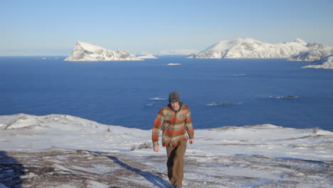 Ein-Mann,-Der-Eine-Verschneite-Landschaft-Mit-Dem-Arktischen-Ozean-Und-Den-Bergen-Im-Hintergrund-Hinaufwandert