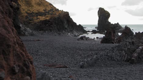 Walking-over-the-black-rock-beach-of-Iceland-by-the-waves---wide-rolling